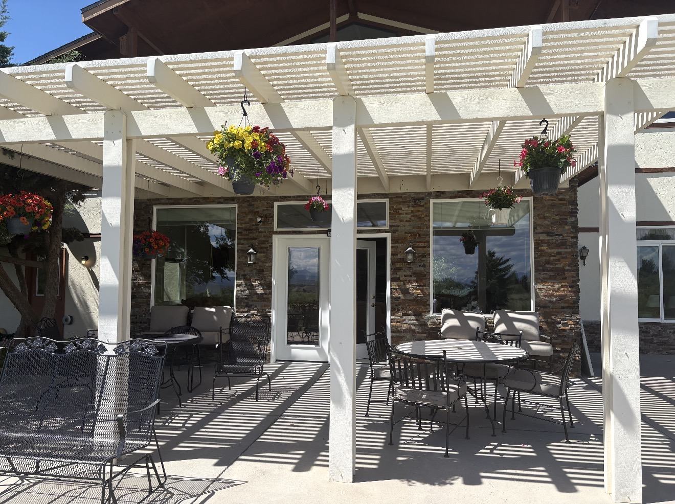 Shaded outdoor patio with tables, seating and hanging flowers